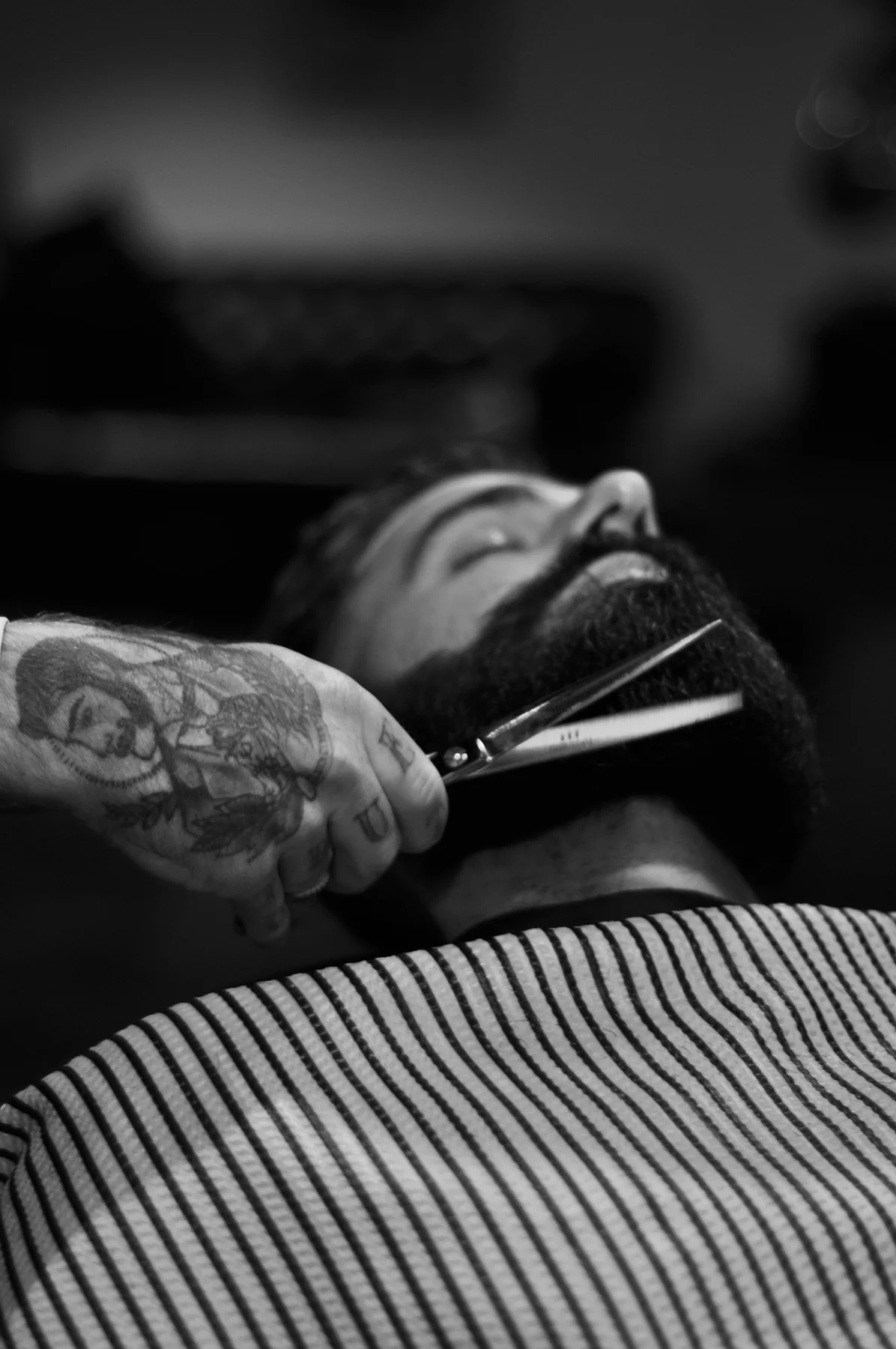 Detalle en blanco y negro del perfilado de una barba con tijeras